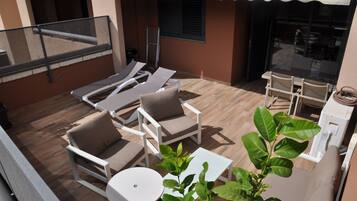 Terraza en la azotea con sillones, una mesa y una pequeña planta.