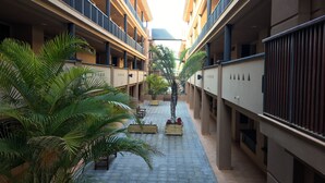 A multi-story hotel corridor with balconies, potted plants, and a central walkway. - Spacious 2 bedroom apartment, large terrace, sea view, Paraiso II complex (Adeje)