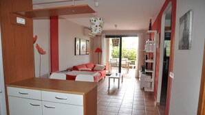 A modern kitchen with white cabinets and a wooden countertop, a red sofa with a white table, and a dining area with a red lamp. - Spacious 2 bedroom apartment, large terrace, sea view, Paraiso II complex (Adeje)
