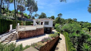 Una casa con muro de piedra, balcón y jardín.