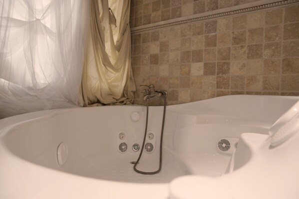 A bathroom with a bathtub, a shower, and a tiled wall.