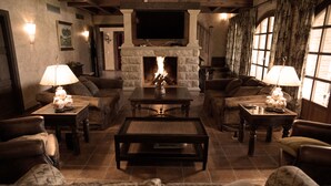 Una sala de estar acogedora con chimenea, sofás de cuero y un televisor montado en la pared.
