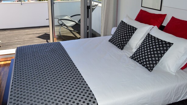 Ein Hotelzimmer mit Bett, Balkon und Meerblick.