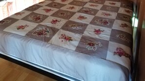 Un dormitorio con techo de madera, una cama con colcha floral y un ventanal con cortinas.