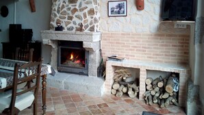 Una habitación acogedora con chimenea de piedra, televisor montado en la pared y una mesa con sillas.