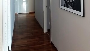 A hallway with wooden flooring, a framed black and white photograph on the wall, and a door at the end. - Splendid Apartment right next to a sandy beach (Split)