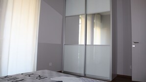 A room with a sliding glass door, a bed with a patterned bedspread, and a door with a lock. - Splendid Apartment right next to a sandy beach (Split)