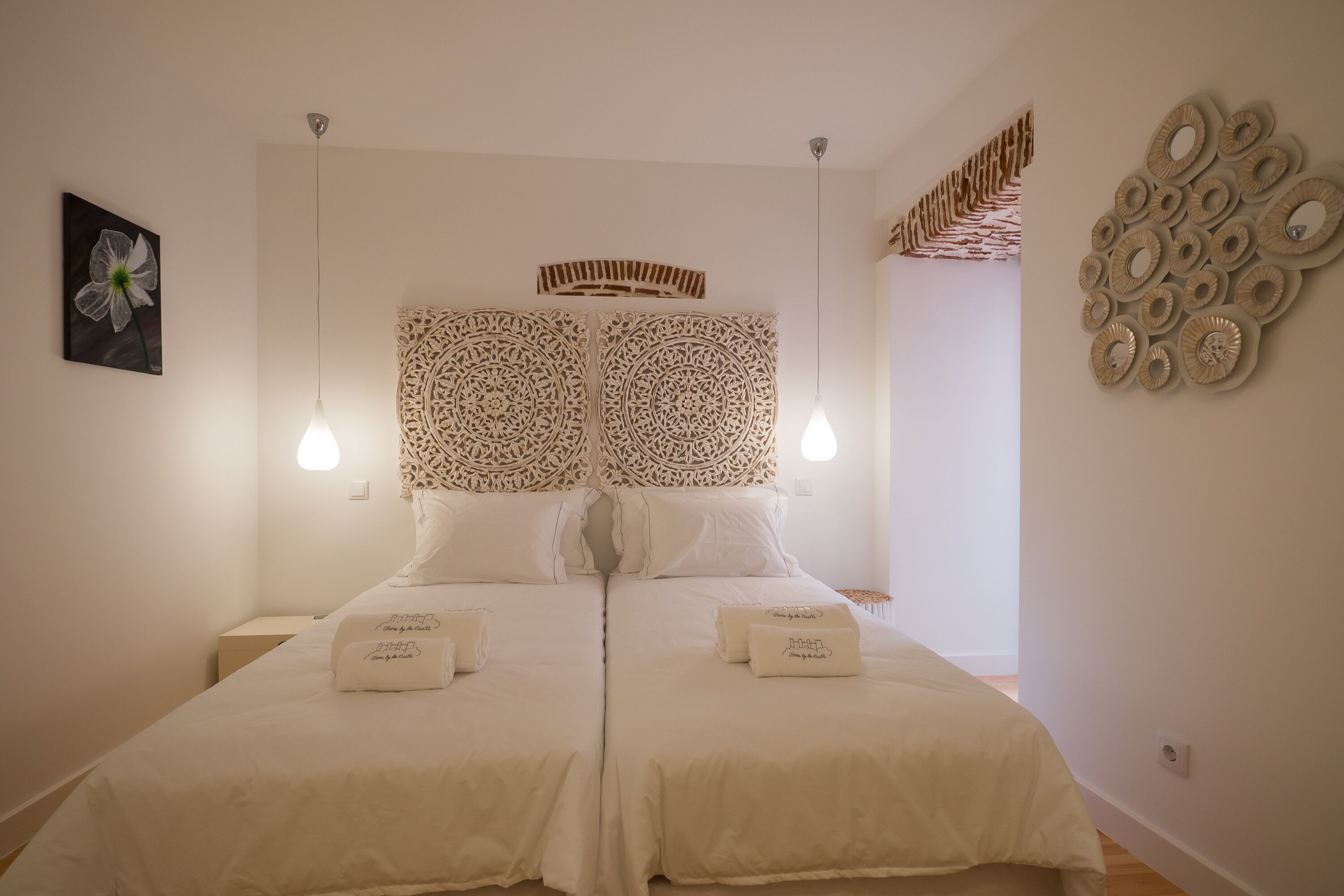 A double bed with a decorative headboard, two bedside tables, and a wall with circular wall art.