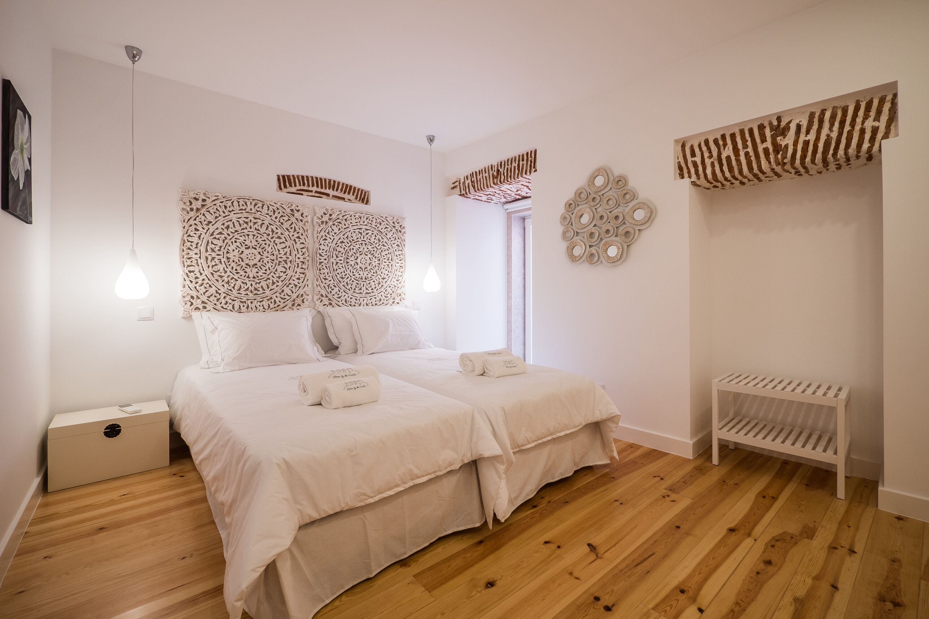 Een slaapkamer met twee bedden, een houten vloer en decoratieve muurkunst.