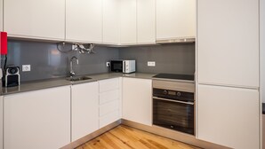 A modern kitchen with white cabinets, a microwave, a sink, and a built-in oven.