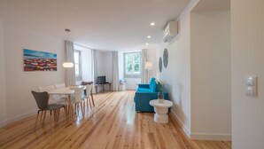 A modern living room with a dining area, a blue sofa, and a white table.