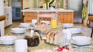 En morgenmadsopsætning med et bord dækket til to, med brød, frugt og et glas appelsinjuice.
