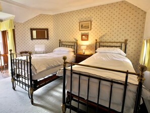 A room with two single beds, a wooden headboard, a nightstand with a lamp, and floral wallpaper. - Lagafater Lodge (Stranraer)