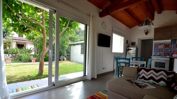A modern living room with a large sliding glass door leading to a garden.