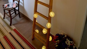 A wooden ladder with lights, a chair, and hats on the wall.