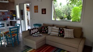 A living room with a sofa, colorful striped rug, and a window with a view of greenery.