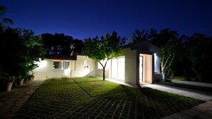 A modern house with a paved lawn and a small tree in the center.