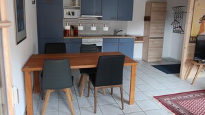 Une cuisine de taille réduite avec des meubles bleus, une table à manger en bois et des chaises noires.