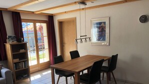 Un coin repas avec une table et des chaises en bois, une bibliothèque, une porte et un tableau encadré au mur.