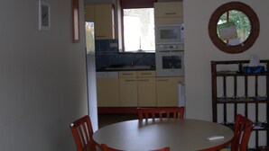 Una cocina compacta con zona de comedor, que incluye una mesa y sillas, y un refrigerador pequeño.