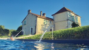 Uma casa com piscina, fonte de água e área gramada.