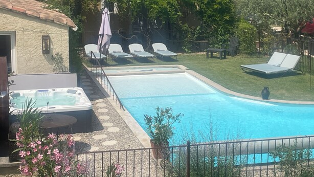 Une piscine avec des chaises longues, un jacuzzi et un chemin en pierre.