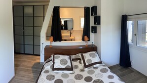 Une chambre à coucher avec un lit, un miroir, une fenêtre et une armoire.