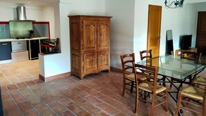 Eine Küche mit Gasherd, integriertem Backofen und Mikrowelle. Es gibt einen Holzkasten und einen Esstisch mit Stühlen.