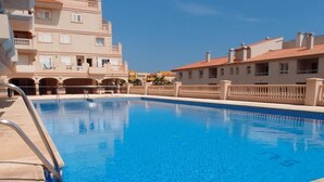 A swimming pool with a clear blue water, surrounded by buildings with balconies and a tiled roof. - Luxery apartment "SEAGULL" - Family friendly - 2 bedrooms (max.4 pers.) (El Ejido)