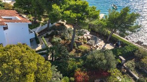A coastal property with a white building, lush greenery, and a view of the sea.