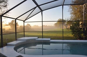 A swimming pool with a glass enclosure, steps leading into the water, and a view of a grassy landscape. - Family-friendly 5BR villa with stunning view and private, south-facing pool (Clermont)
