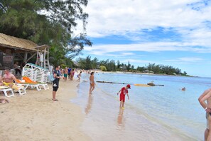 Une plage avec des gens, une tour de surveillance pour les sauveteurs et un toboggan aquatique.