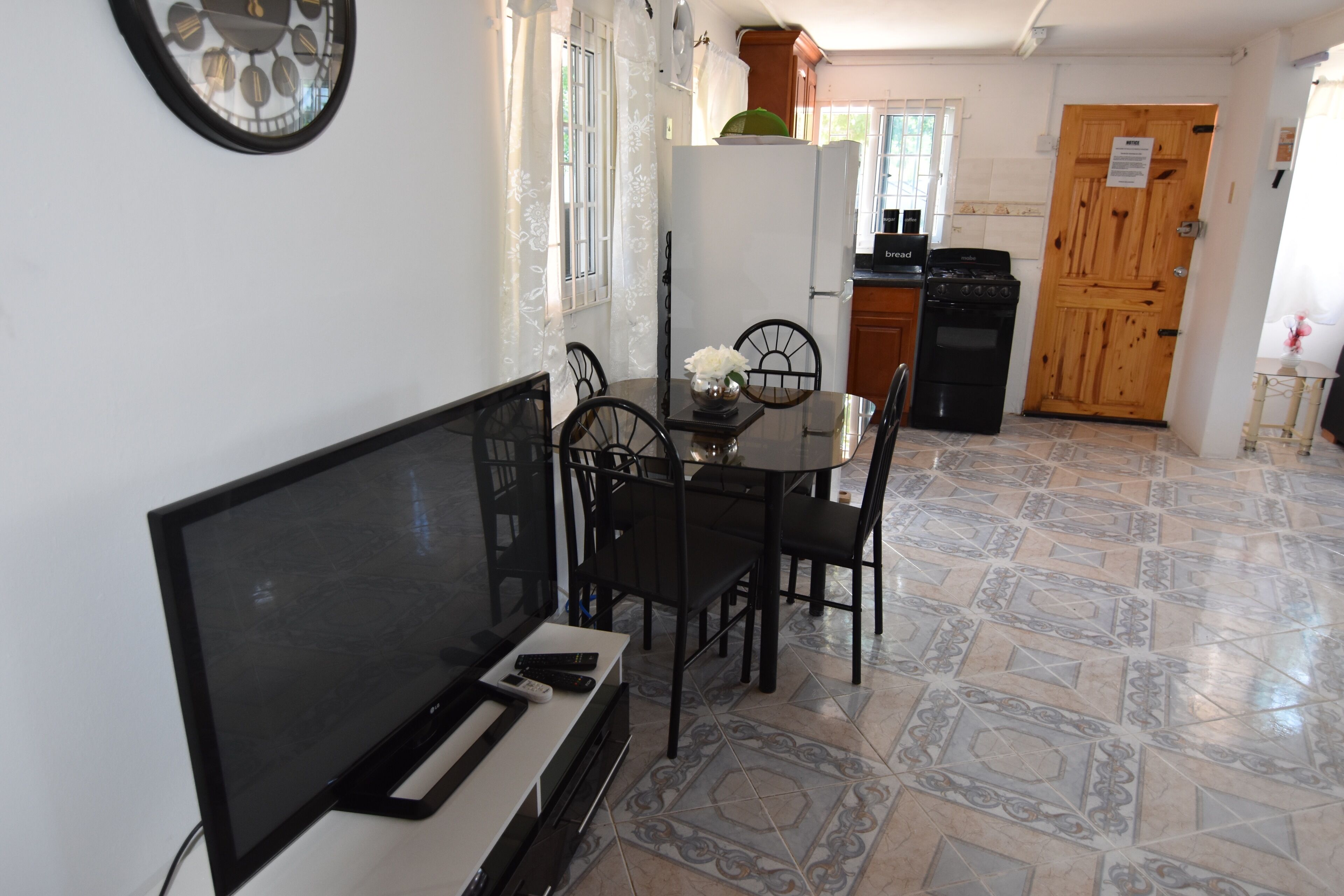 A dining area with a TV, remote, and a vase of flowers on the table.