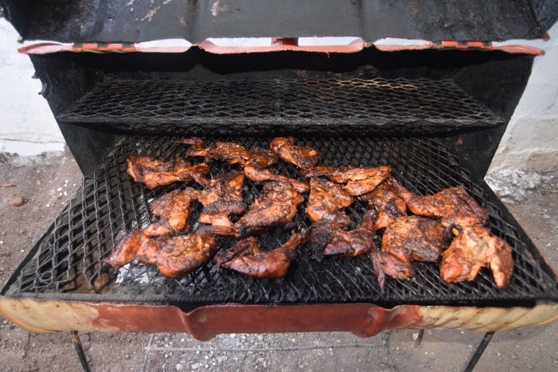 A grill with several pieces of meat being cooked.