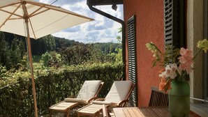 Eine Terrasse mit Holzmöbeln, einem Tisch und einem Stuhl unter einem Sonnensegel.