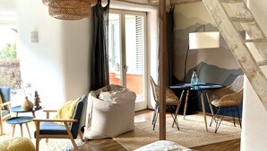 Ein gemütliches Schlafzimmer im Loft-Stil mit Bett, Sitzgelegenheit und Esstisch.