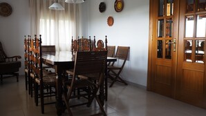 A dining room with a wooden table and chairs, a chandelier, and a wooden door with glass panels. - House with wonderful views in the heart of Ciudad Rodrigo. " The cherry tree " (Cdad. Rodrigo)