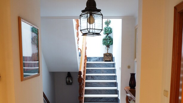 A staircase with a wooden handrail leading to a landing with a potted plant. - House with wonderful views in the heart of Ciudad Rodrigo. " The cherry tree " (Cdad. Rodrigo)