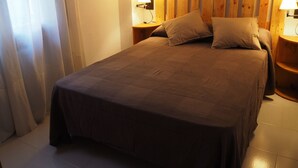 A neatly made bed with a wooden headboard, two bedside lamps, and a window with curtains. - House with wonderful views in the heart of Ciudad Rodrigo. " The cherry tree " (Cdad. Rodrigo)