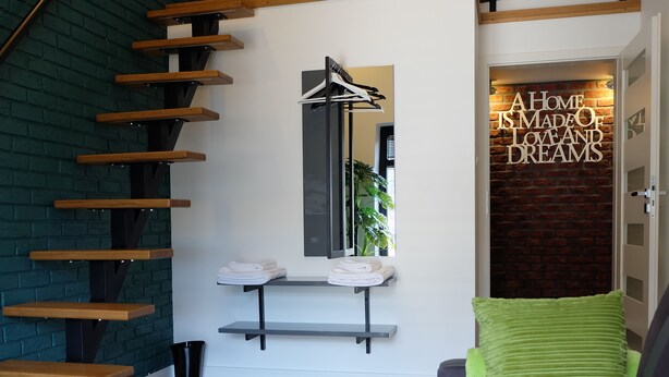 Een moderne woonruimte met een trap, een bank, een salontafel met decoratieve objecten en een muur met een motiverende quote.