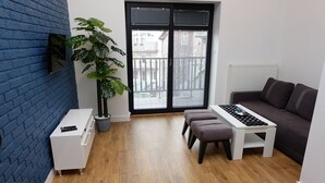 Een moderne woonkamer met een blauwe bakstenen muur, een grote potplant, een donkerbruine bank, een witte salontafel en een klein wit kastje.