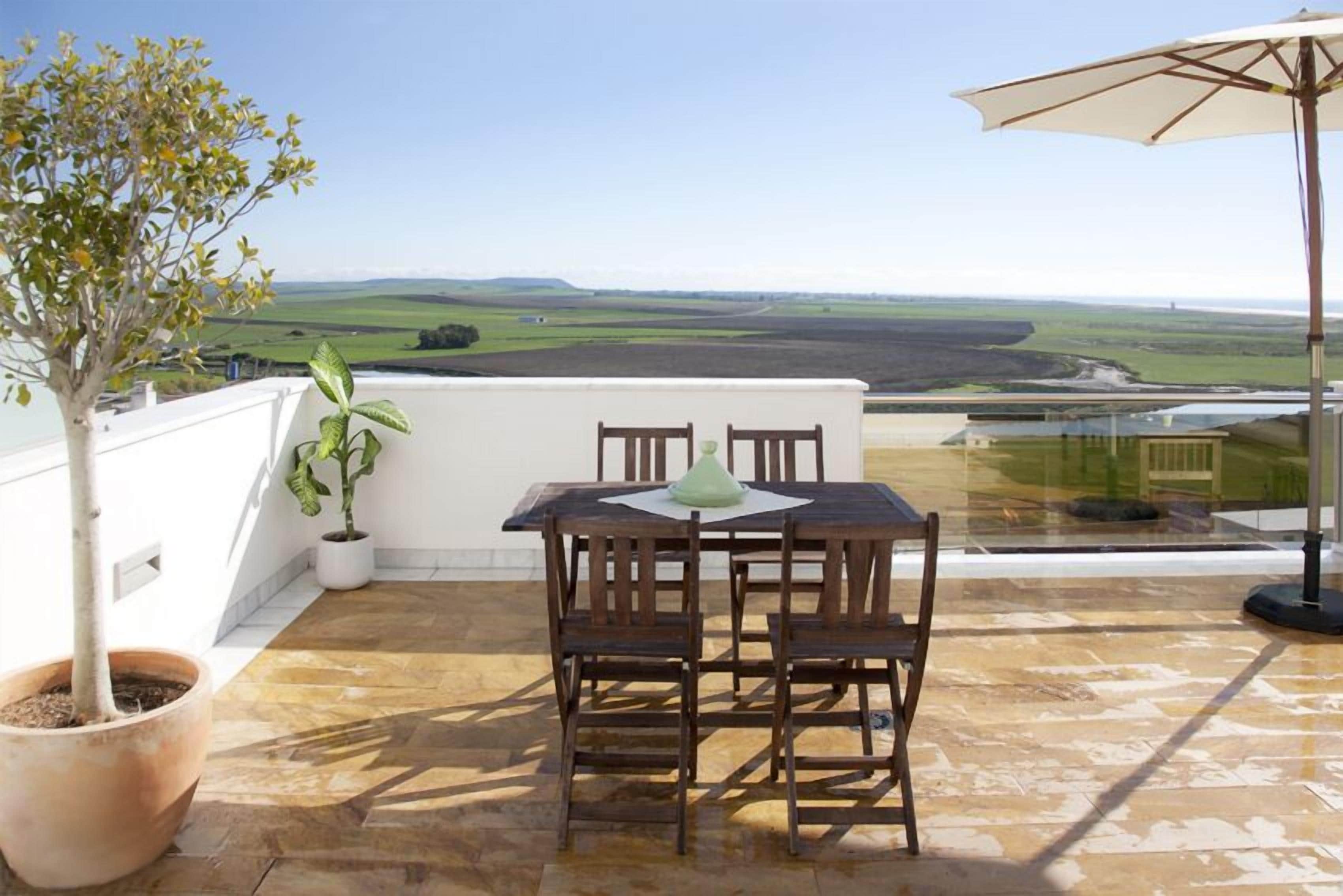 Een terras met een tafel, stoelen, een potplant en uitzicht op het landschap.