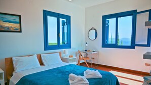 Ein Schlafzimmer mit einem Bett, zwei Fenstern, einem Schreibtisch, einem Stuhl, einem Spiegel und einem Bild an der Wand.