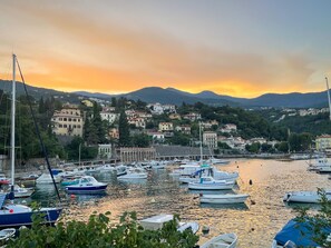 A marina with boats docked, surrounded by hillside buildings and a sunset in the background. - Nature idyll with sea views of the Kvarner bay (Poljane)