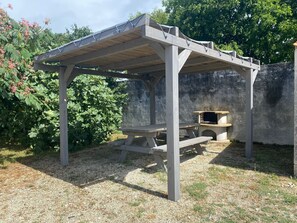 A wooden pergola with a built-in barbecue area.