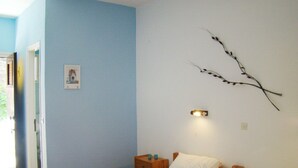 Um quarto com cama, mesa de cabeceira e luminária na parede.