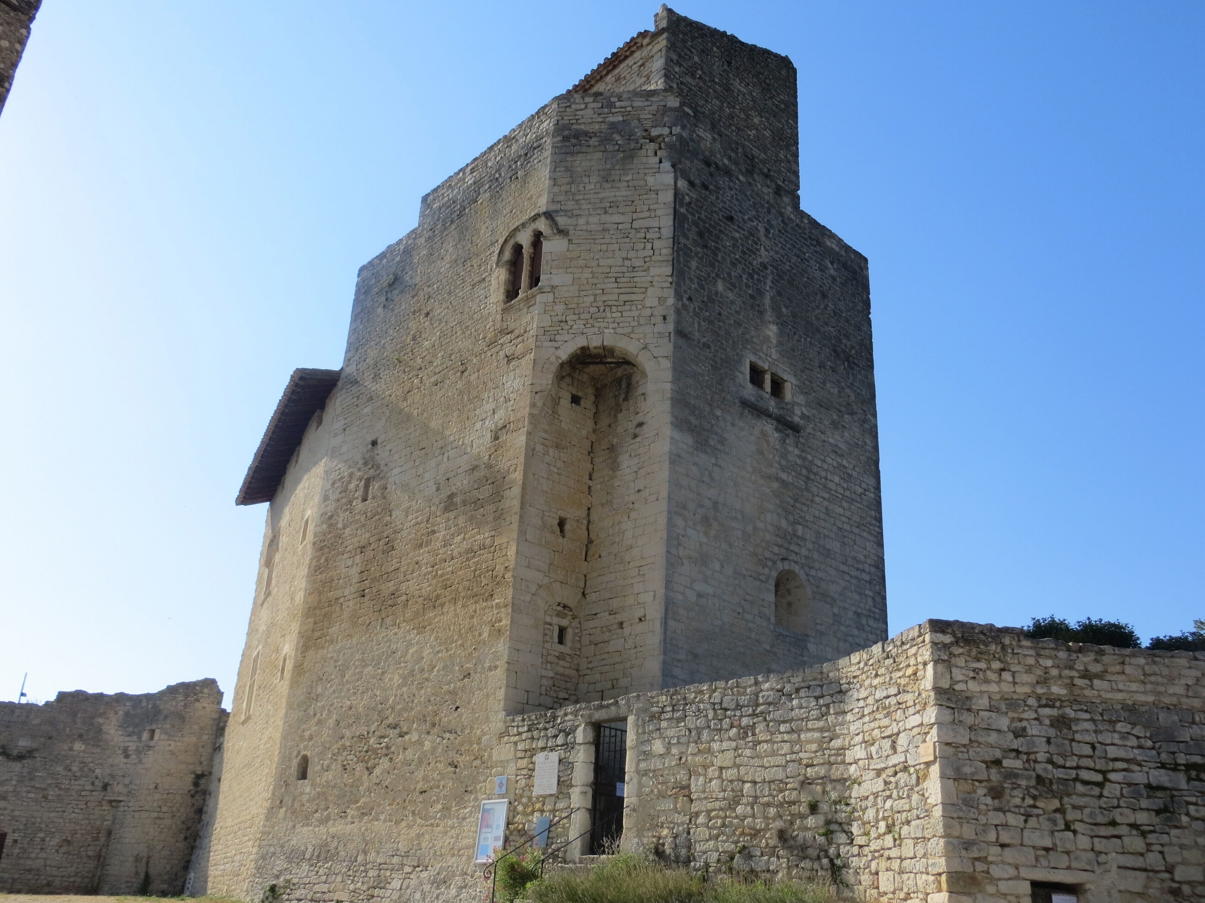 Ein historischer SteinTurm mit rundbogigen Fenstern und einem schmalen Eingang, umgeben von anderen SteinGebäuden.