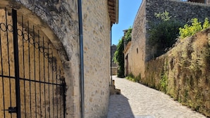 A cobblestone street with stone buildings, a metal gate, and a clear blue sky. - Le Mas des Restanques 3*,located in one of the most beautiful villages in France (Le Poët-Laval)