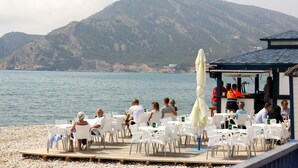 Ein Restaurant am Meer mit Terrassenplätzen und Blick auf das Meer und ein Bergpanorama.
