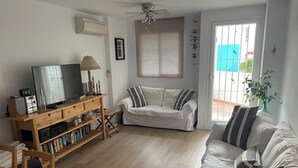Ein Wohnzimmer mit einem Holz-Fernsehschrank, einer Couch und einem Esstisch.